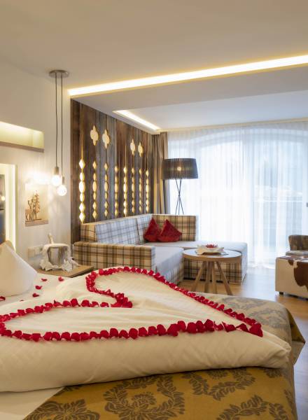 Rosenblätter in Herzform auf Hotelbett