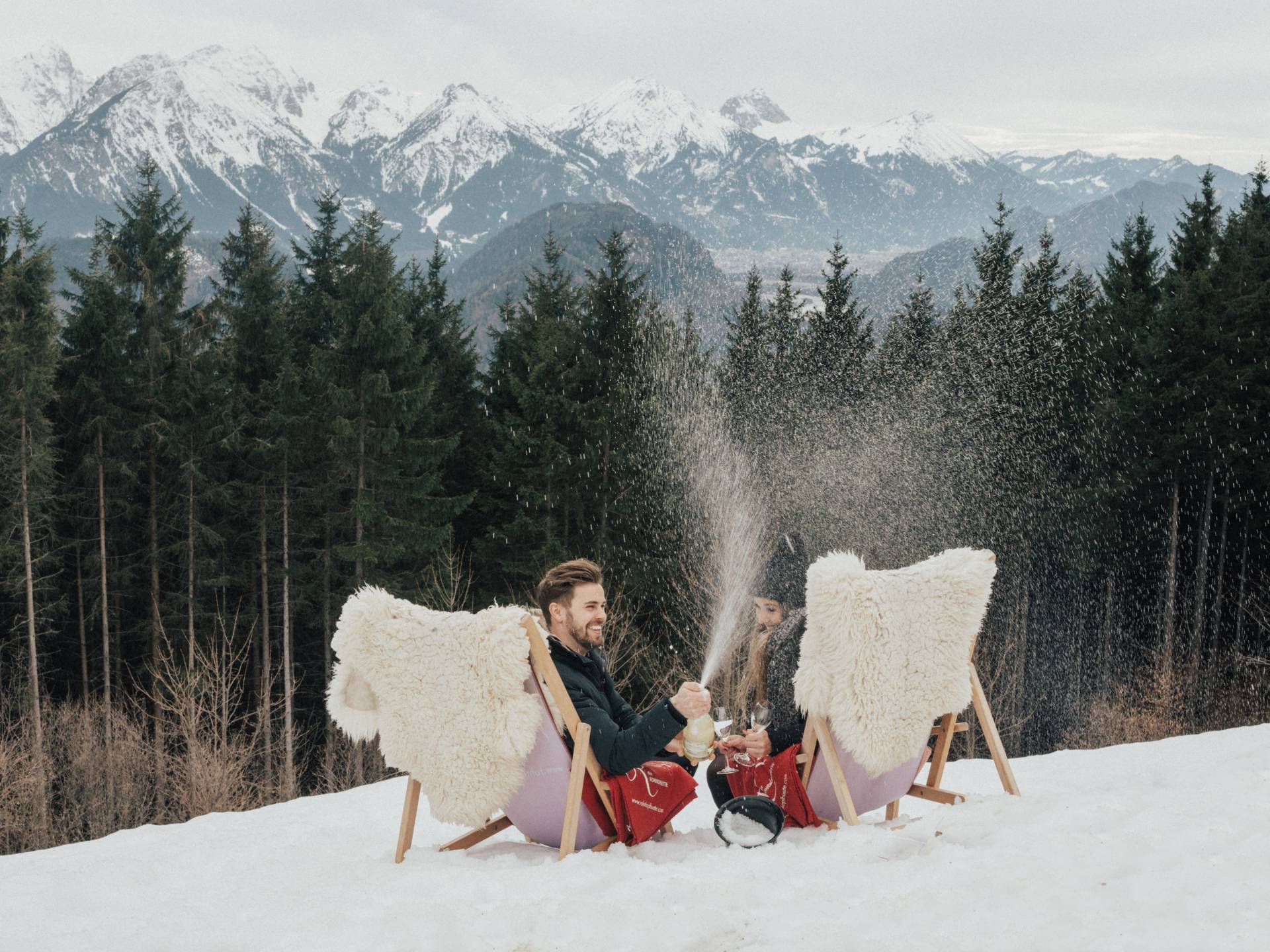 Urlaubsideen für Verliebte - Paar sitzen in Stuhl und lassen Sektkorken knallen