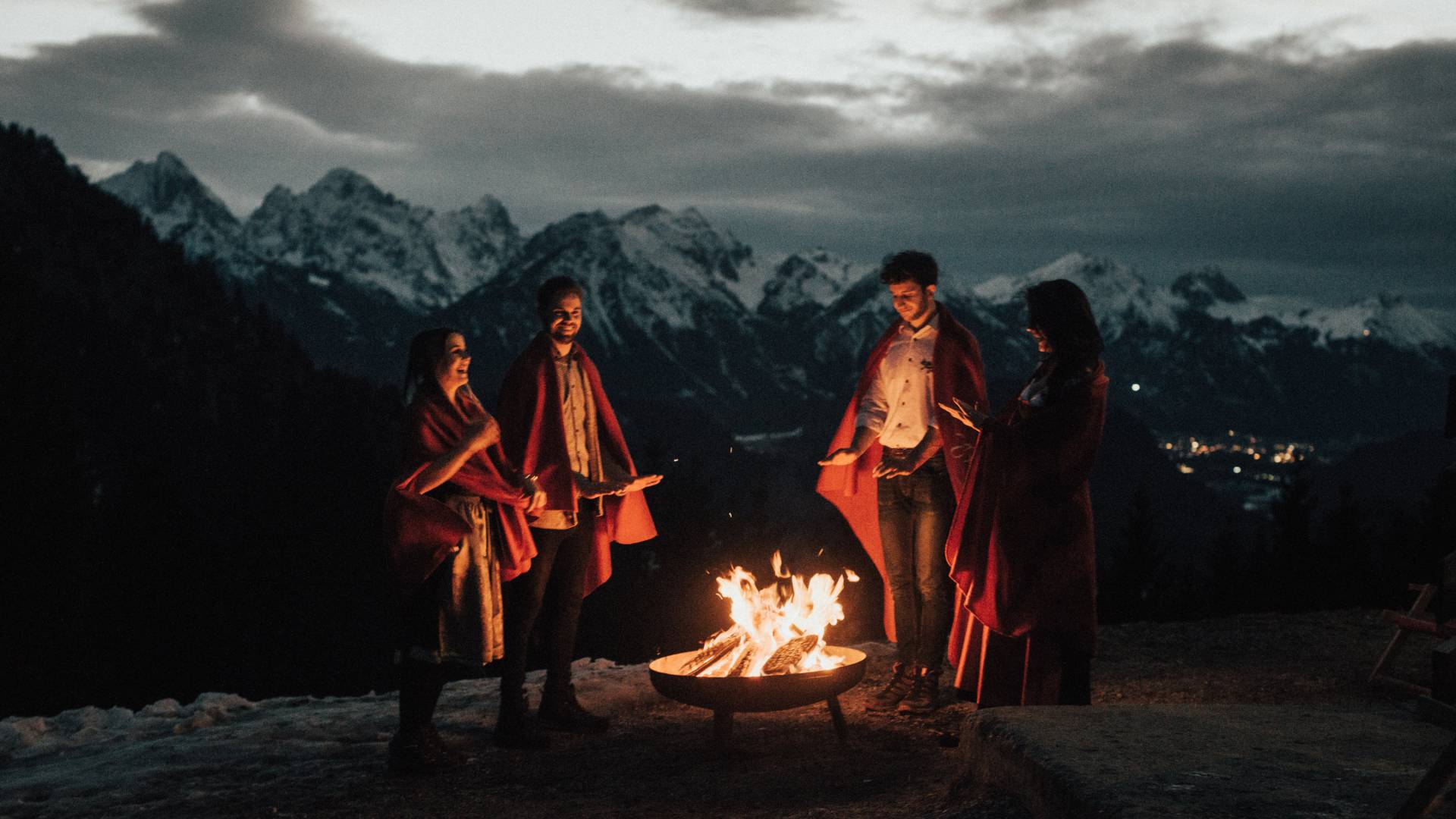 Zeit mit Freunden im Allgäu - Freundesgruppe steht um Lagerfeuer in den Bergen