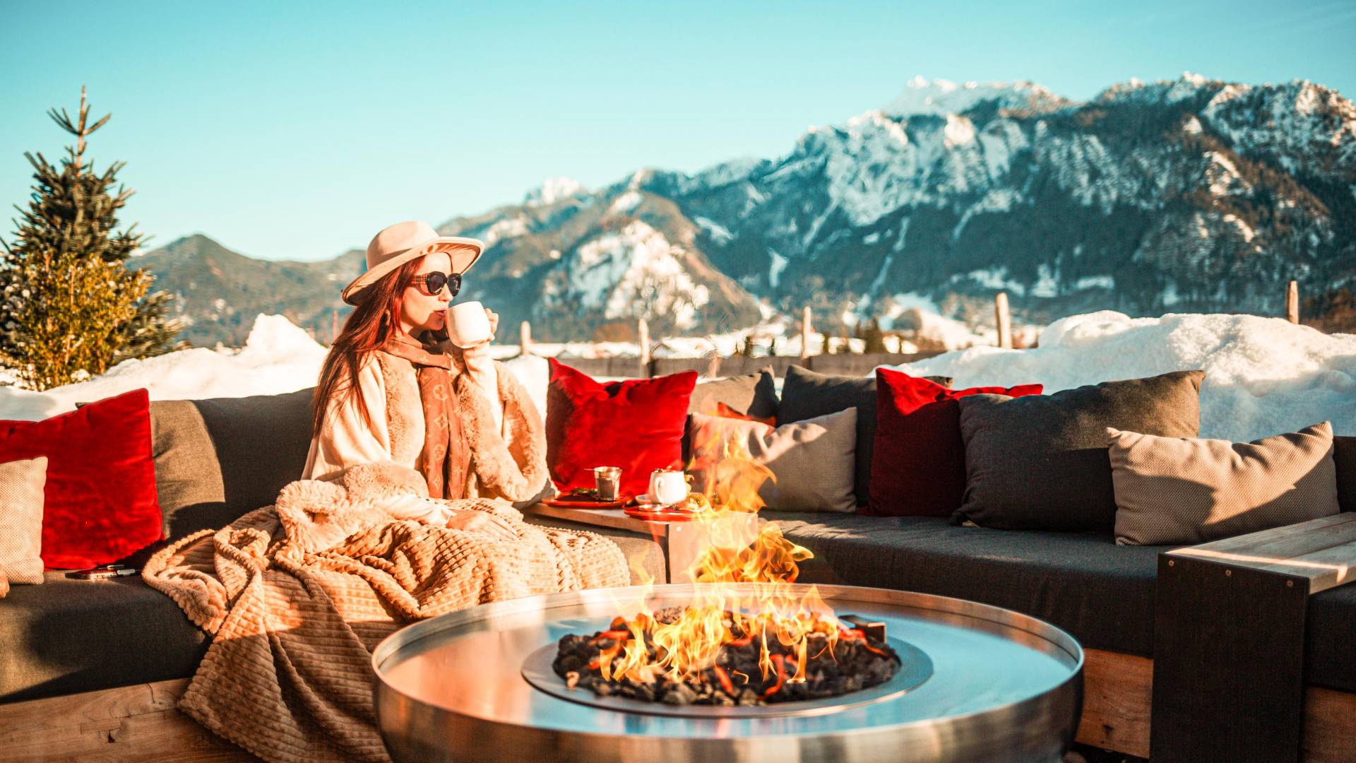 Wellnessurlaub im Winter: Frau an Feuerstelle vor Neuschwantein