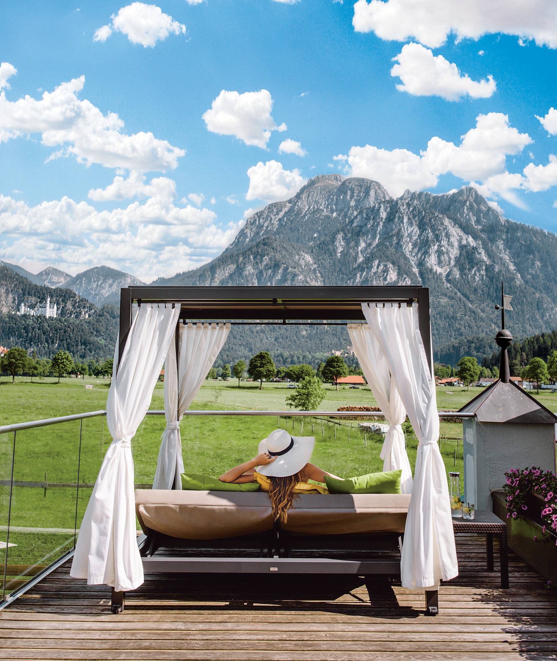 Wellnessurlaub im Allgäu - Frau in Dailybett entspannt mit Blick auf das Schloss und die Berge