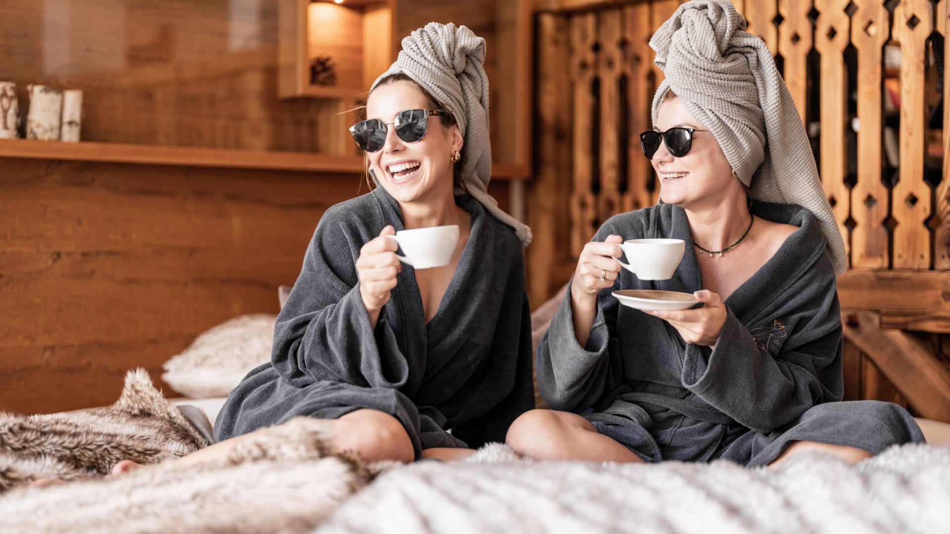 Ayurveda Retreat - Freundinnen in Bademantel entspannen bei einer Tasse Kaffee
