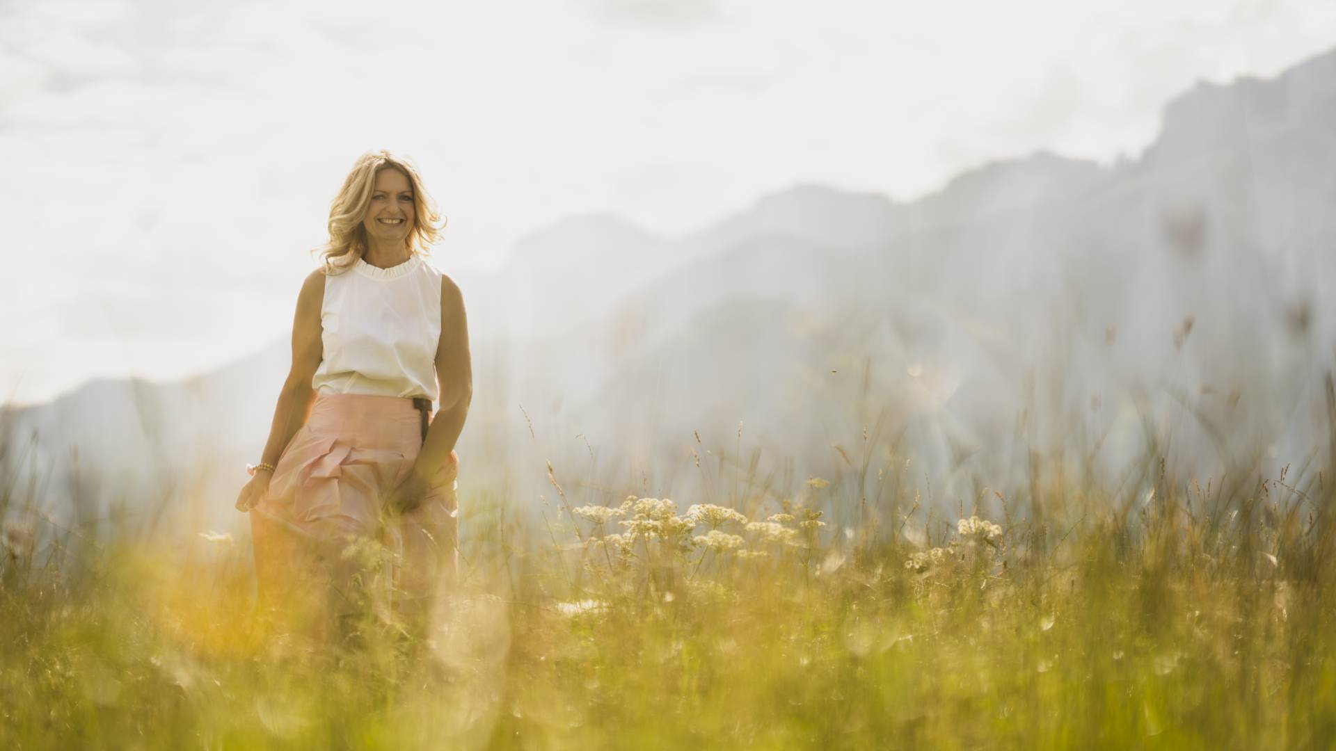 Ayurveda im Allgäu - Hotelmitarbeiterin spaziert über Felder im Sommer