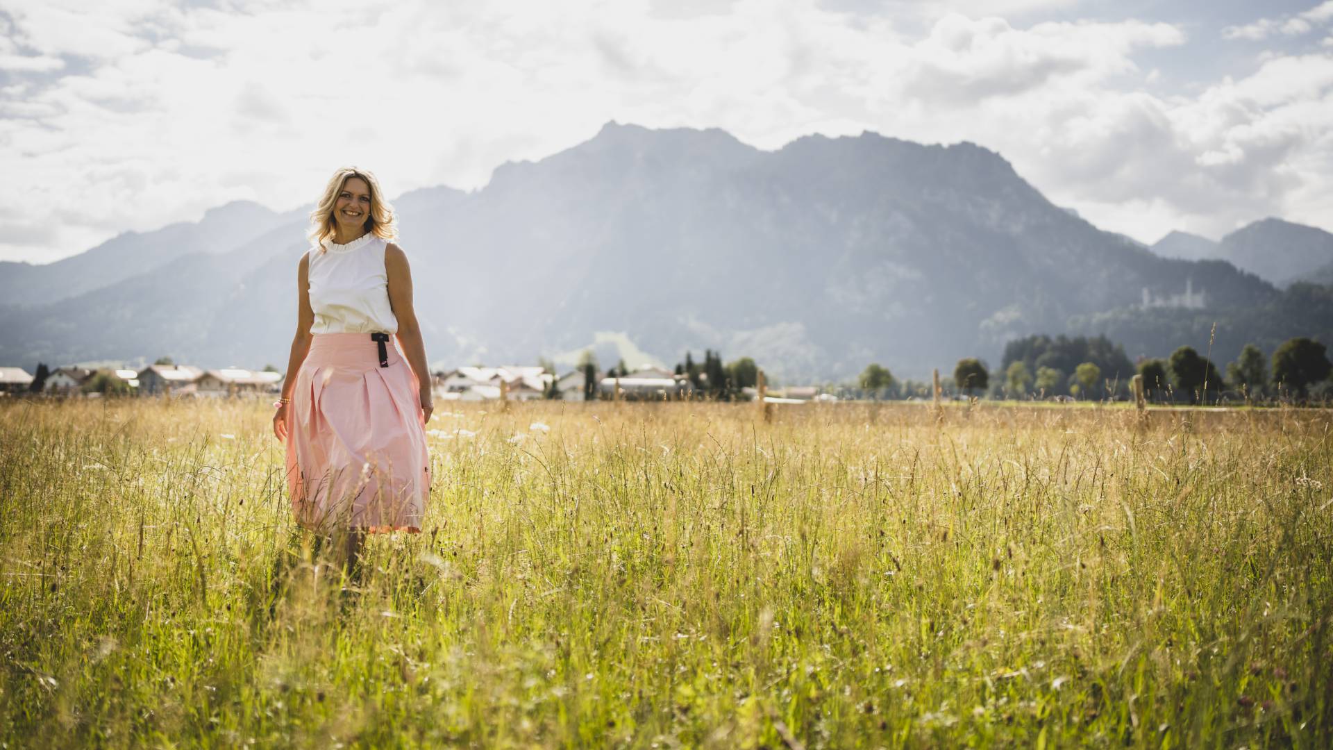 Alpen Ayurveda - Frau in Feld mit Bergen im Hintergrund