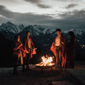 Zeit mit Freunden im Allgäu - Freundesgruppe steht um Lagerfeuer in den Bergen