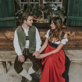 Zeit zu zweit im romantischen Hotel das Rübezahl im Allgäu -  Paar in Tracht sitzt verliebt auf einer Holzbank