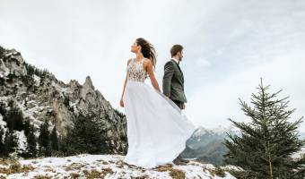 Hochzeitspaar steht auf einem Berg im Winter