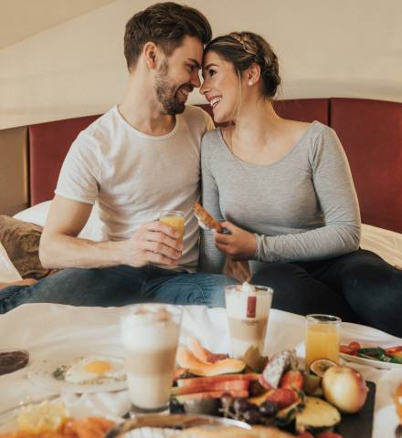 Paar genießt Frühstück im Hotelbett