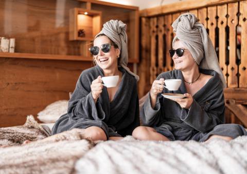 Ayurveda Retreat - Freundinnen in Bademantel entspannen bei einer Tasse Kaffee