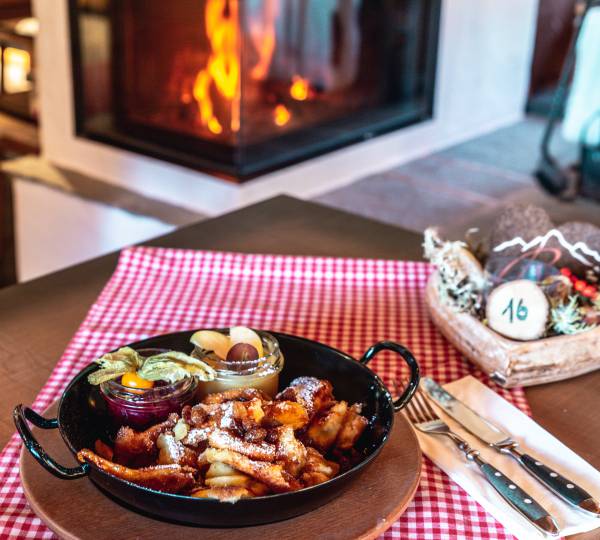 Kaiserschmarrn in Gusseisenpfanne auf Tisch vor Karmin