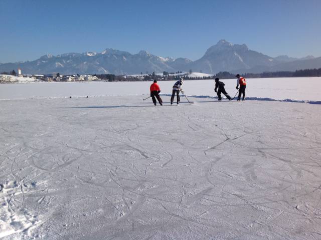Personen spielen Eishockey auf See in Schwangau