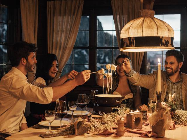 Hotel mit Berghütte im Allgäu - Freunde essen Fondue in gemütlichen Ambiente